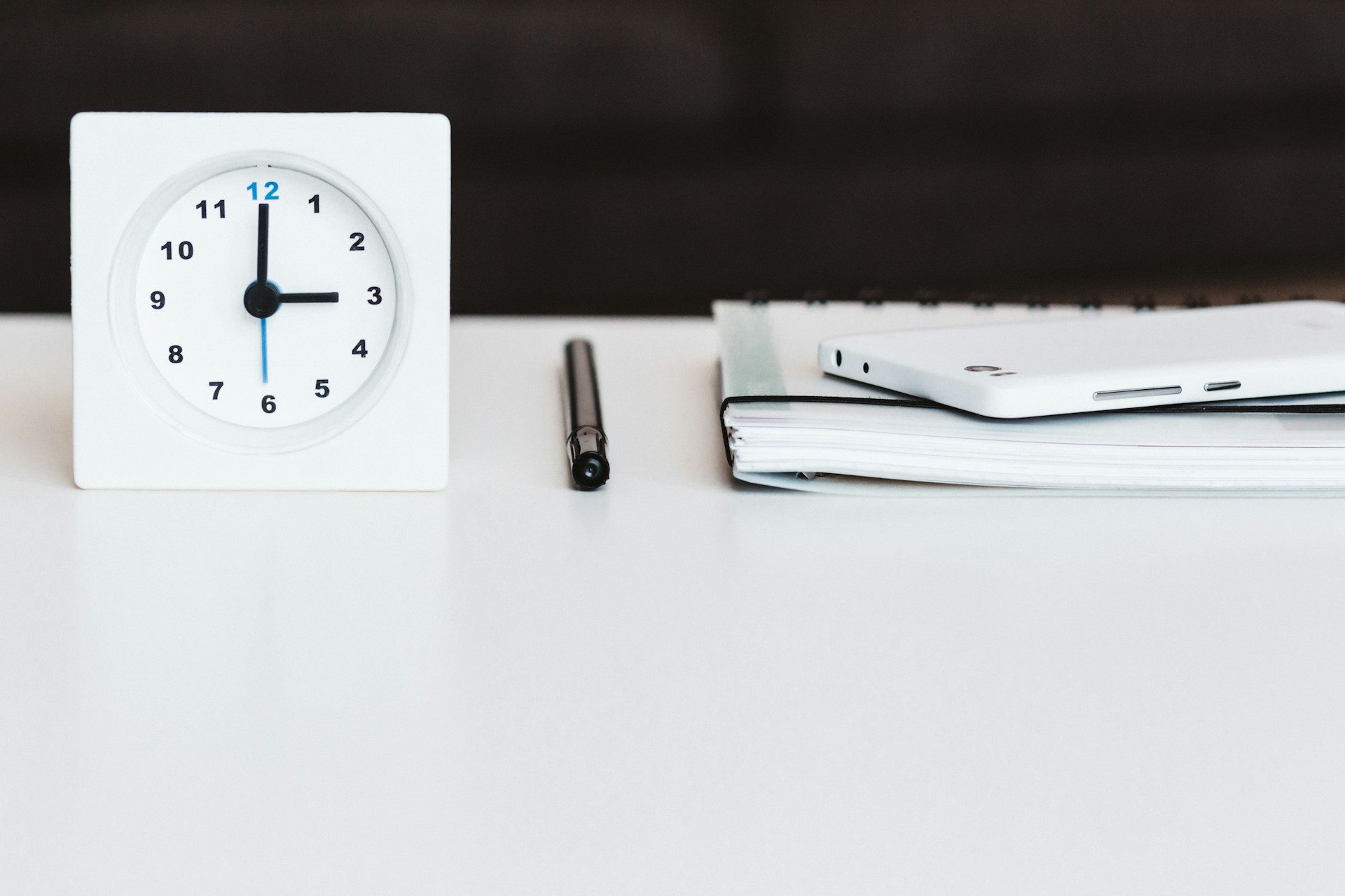 Photo d'une mini-pendule posée sur un bureau avec un planning éditorial